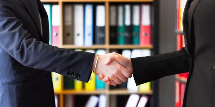 Two business people shaking hands at a mortgage brokerage.