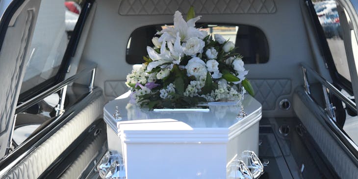 Coffin with flowers inside a hearse.