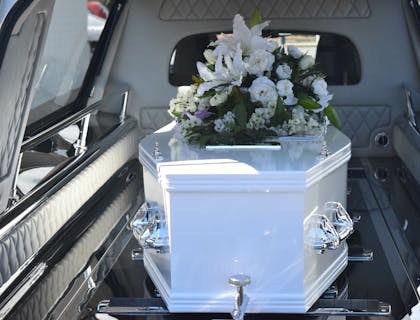 Ataúd con flores dentro de un coche fúnebre en un negocio de servicios funerarios.