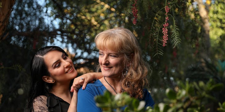 a daughter leans on her mother's shoulder in a forest setting