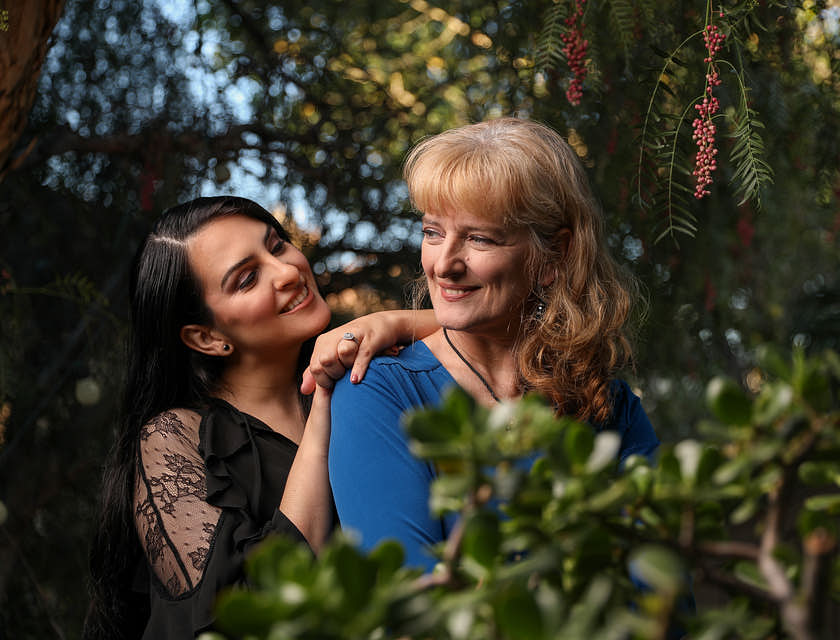 a daughter leans on her mother's shoulder in a forest setting