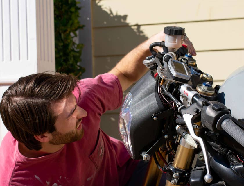 Un uomo che ripara una moto dentro un'officina di riparazione per moto.