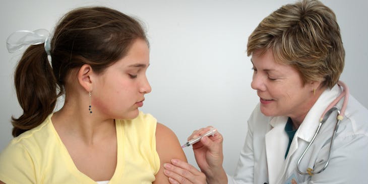 doctor injects a seated patient in her healthcare office