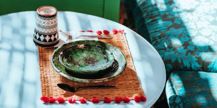 Moroccan-style blue tables and pillow seats set with colorful pottery dishes.