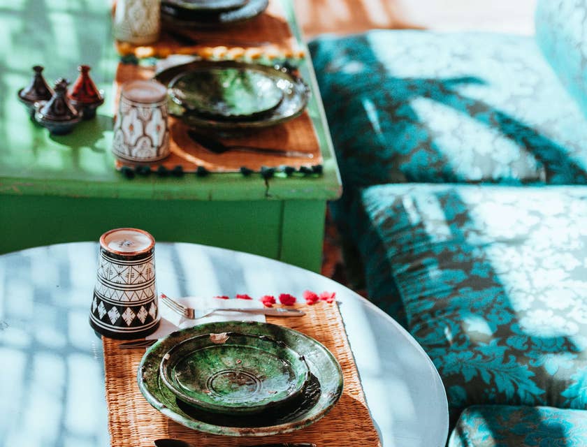 Mesas azules de estilo marroquí y asientos acolchados con coloridos platos de cerámica en un restaurante marroquí.