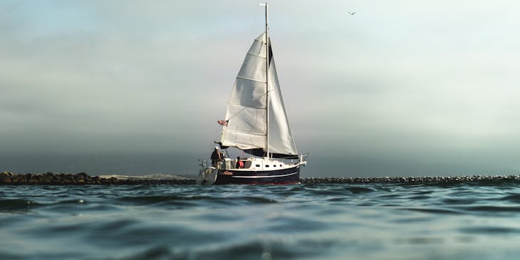 A nautical vessel sails out of a harbor.