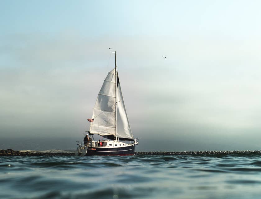 A nautical vessel sails out of a harbor.