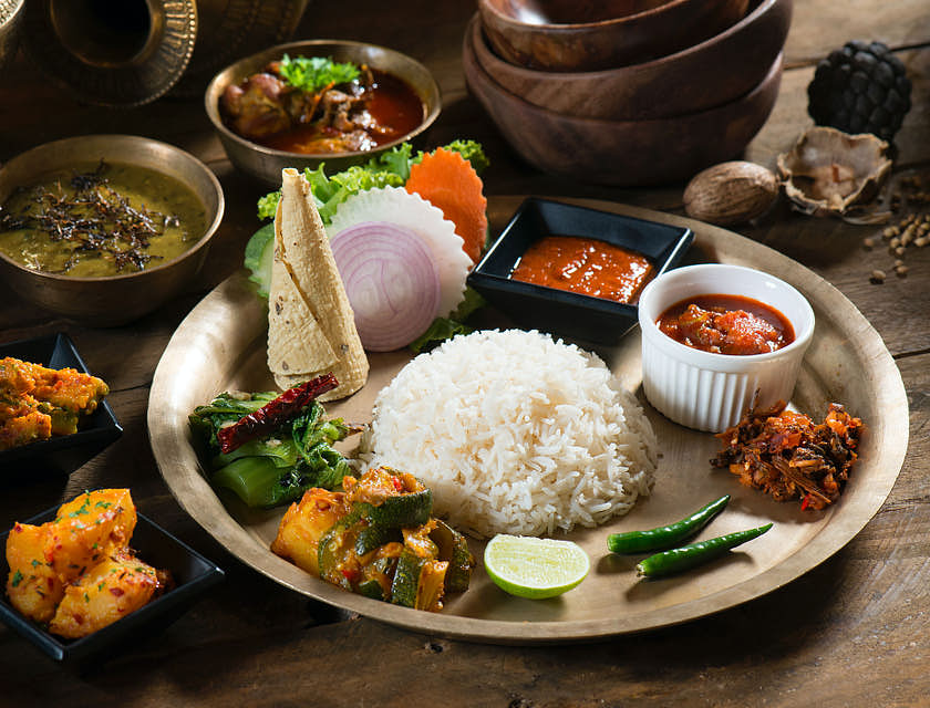 Alcune specialità nepalesi servite in dei piatti sul tavolo di un ristorante nepalese.