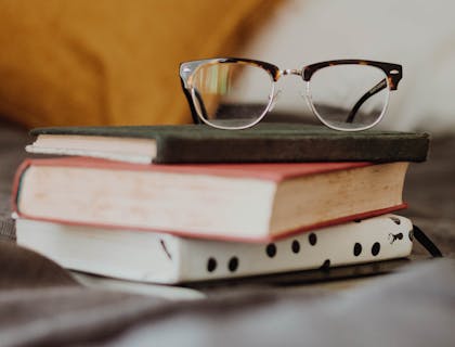 Un paio di occhiali poggiati su dei libri.