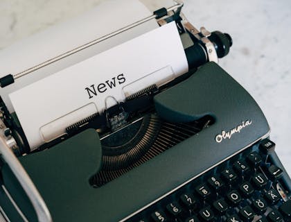 Una máquina de escribir que imprime una página con el título "Noticias" en una empresa de noticias.