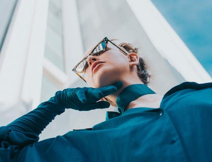 La imagen de una mujer con gafas de sol y vistiendo un traje elegante en un negocio con un nombre de clase alta.