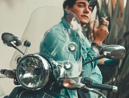 Chico motociclista fumando un cigarro afuera de un bar de moteros