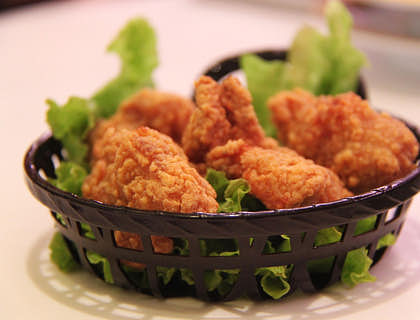 Un plato con piezas de pollo sobre una cama de lechuga en una broastería.