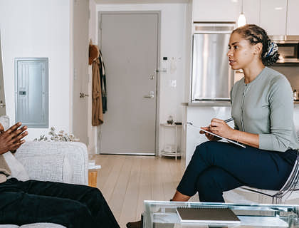 Un hombre sentado en un consultorio recibiendo terapia de un psicóloga en un centro terapéutico.