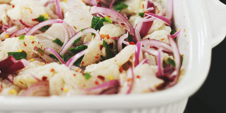Un plato hondo y blanco con una porción generosa de ceviche en una cevichería.