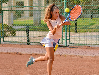 Una joven jugando tennis en un club de esparcimiento.