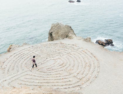 Una persona caminando en una playa de arena blanca en un retiro de un club espiritual.