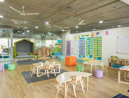 Salón de daycare con diversas mesas infantiles y juegos didácticos.