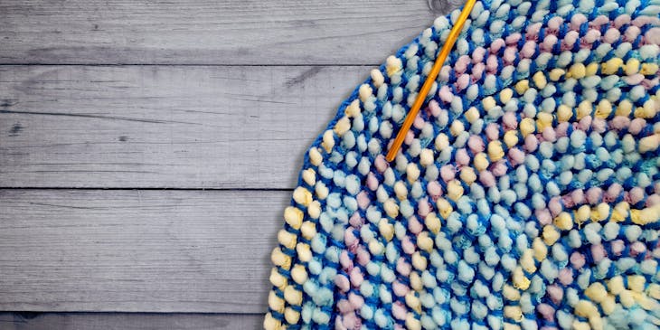 Una aguja de tejido sobre un tapete de colores en un emprendimiento de tejidos.