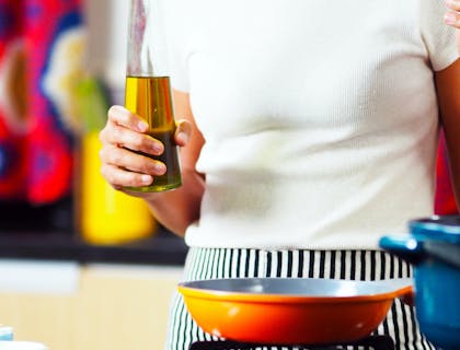 Una mujer sosteniendo una botella con aceite de soja en su mano derecha en una cocina dentro de una empresa de aceite de soja.
