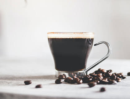 Una taza de café con granos de café a un lado en una empresa de café cubano.