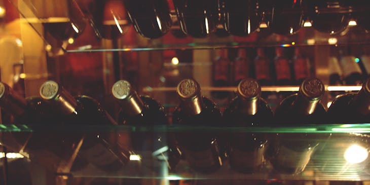 Unas botellas de vino con tapón dorado acostadas en una cava de vino.