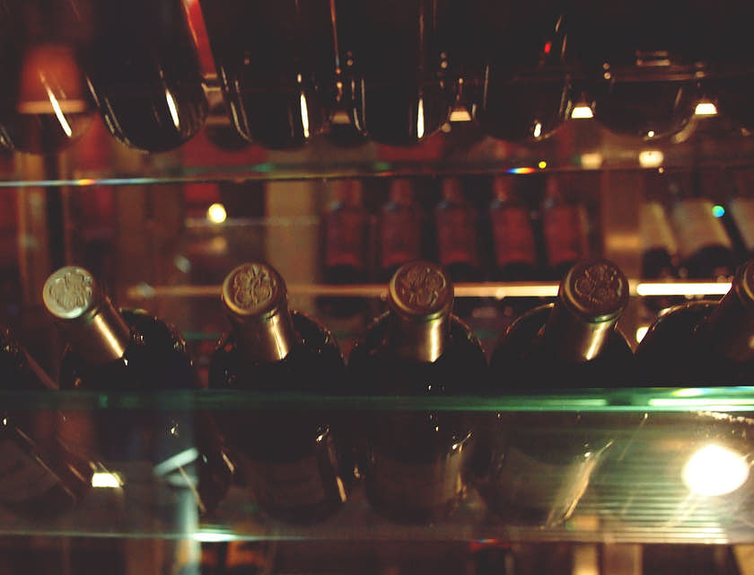 Unas botellas de vino con tapón dorado acostadas en una cava de vino.