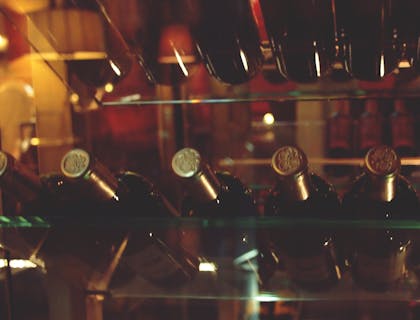 Unas botellas de vino con tapón dorado acostadas en una cava de vino.