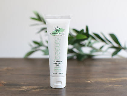 Un tubo de loción corporal sobre una mesa de madera y unas hojas al fondo en una empresa de lociones.