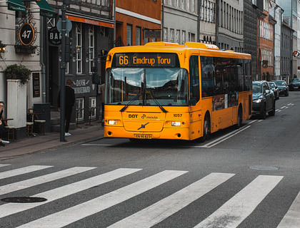 Un metrobús amarillo y negro, de una empresa de metrobuses, recogiendo pasajeros en una ciudad.