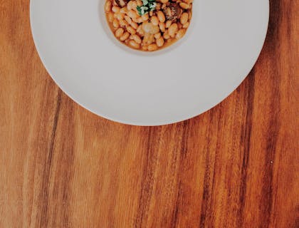 Plato blanco con pallar de Ica y perejil sobre una superficie de madera.