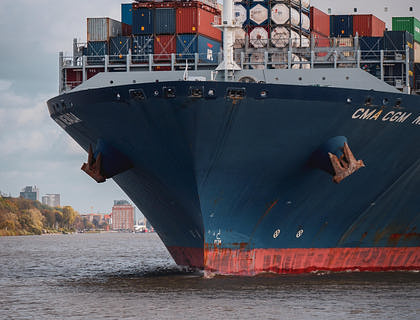 Un barco azul y rojode una empresa de transporte marítimo transportando productos a otras locaciones.