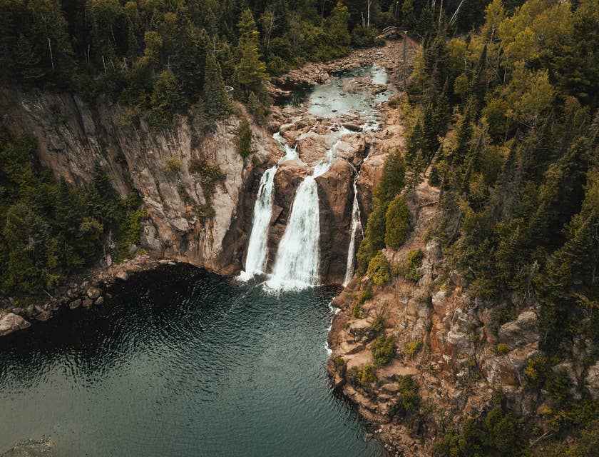 La vista desde arriba de tres cascadas y un lago abajo con pinos alrededor en un viaje ecológico de una empresa de viajes ecológicos.