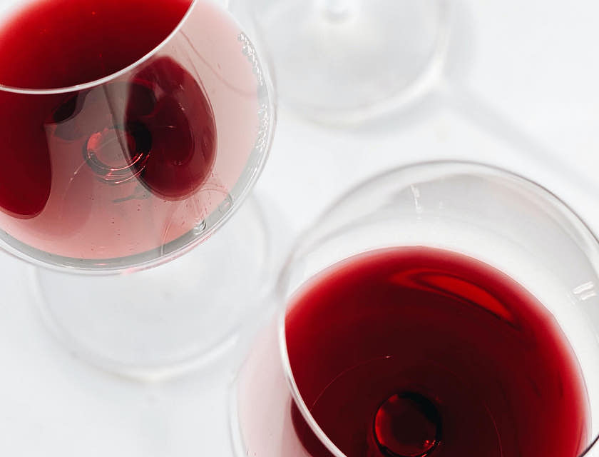 Tres copas servidas con vino de una empresa de vino de San Juan sobre un fondo blanco.