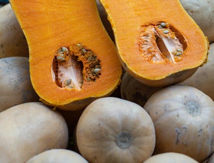 Un zapallo loche partido por la mitad con verduras exhibidas al fondo en una empresa de zapallo de loche de lambayeque..