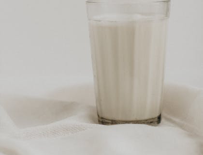 Un vaso con leche sobre un mantel blanco en una empresa lechera.