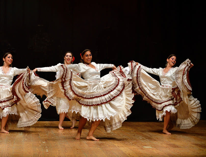 Cuatro mujeres con vestuarios típicos de su región bailando sobre un escenario en una escuela de baile joropo.
