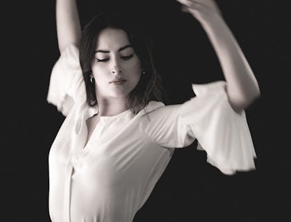 Una mujer vestida de blanco bailando en una escuela de pasodoble.