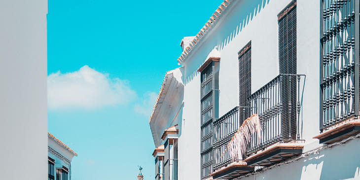 Calle empedrada con vista de una fonda española y una iglesia al fondo.