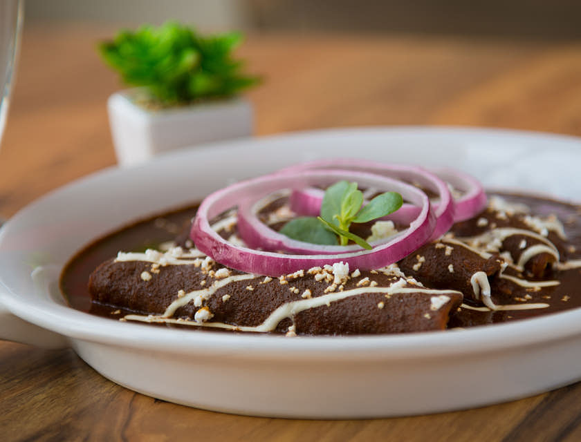 Un plato con enmoladas sobre una mesa de madera en un negocio de mole
