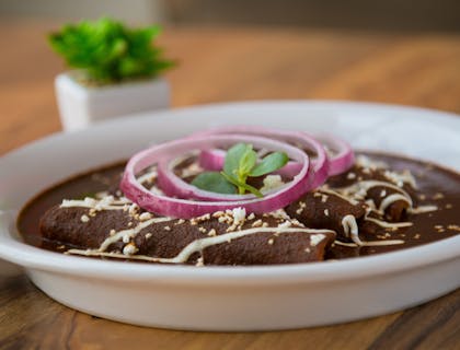 Un plato con enmoladas sobre una mesa de madera en un negocio de mole.