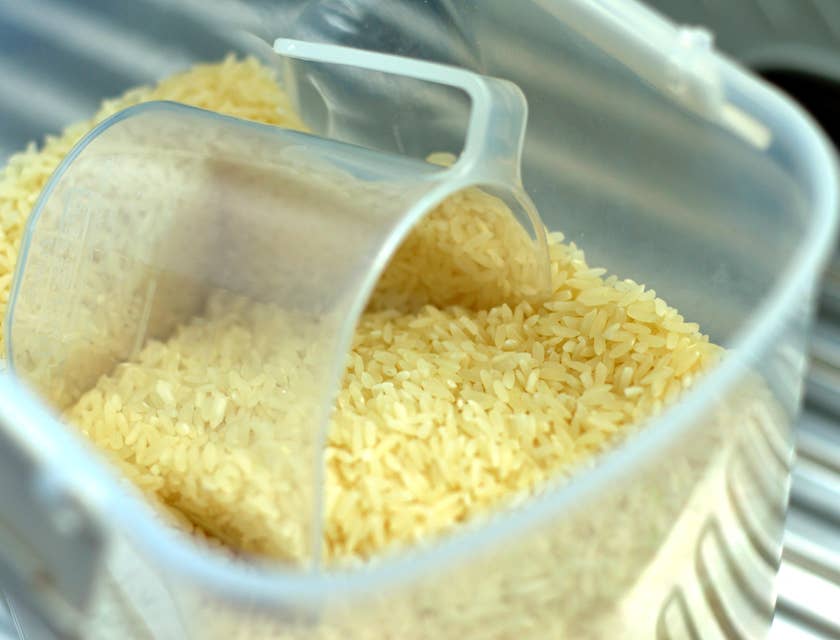 Una taza medidora dentro de una vasija con arroz crudo en un negocio de arroz mamposteao.