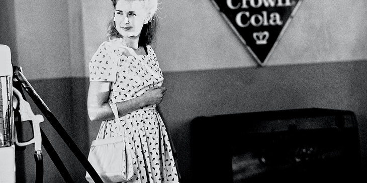La fotografía a blanco y negro de una mujer de los años cincuenta en un negocio de arte nostálgico.