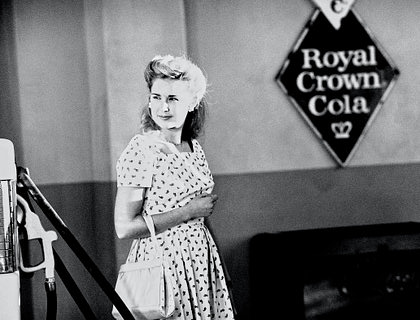 La fotografía a blanco y negro de una mujer de los años cincuenta en un negocio de arte nostálgico.