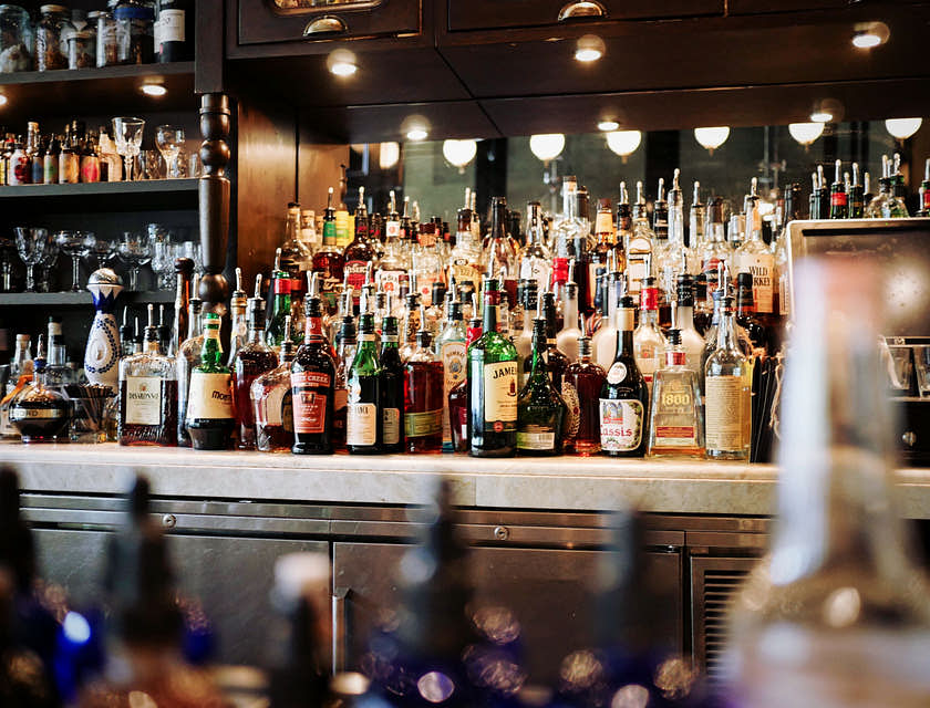 Muchas botellas encima de una barra en un negocio de bebidas alcohólicas.