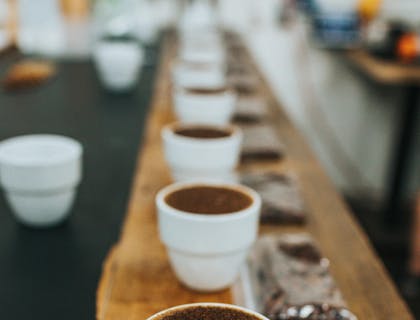 Tazas con cacao en polvo y bolsas de plástico con semillas de cacao sobre una barra de madera en un negocio de cacao arriba.