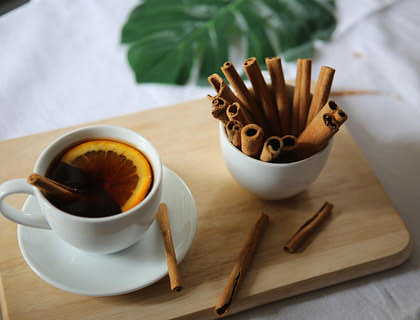 Taza de té con canelazo, lima y varitas de canela sobre una mesa de madera en un negocio de canelazo