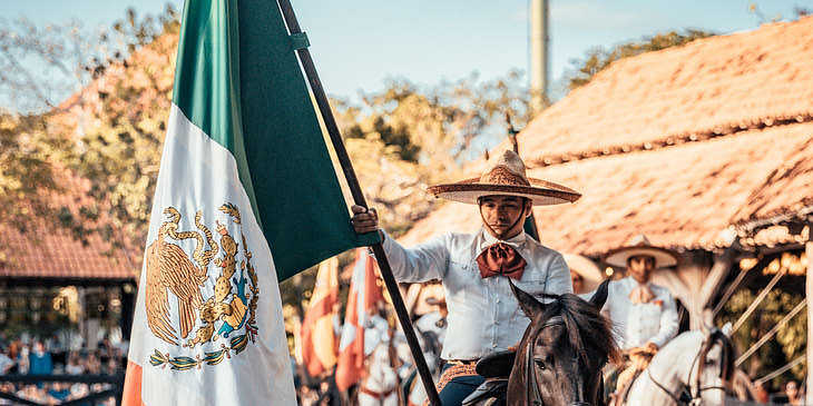 Un charro montando en un caballo con la bandera de México en un negocio de charrería.