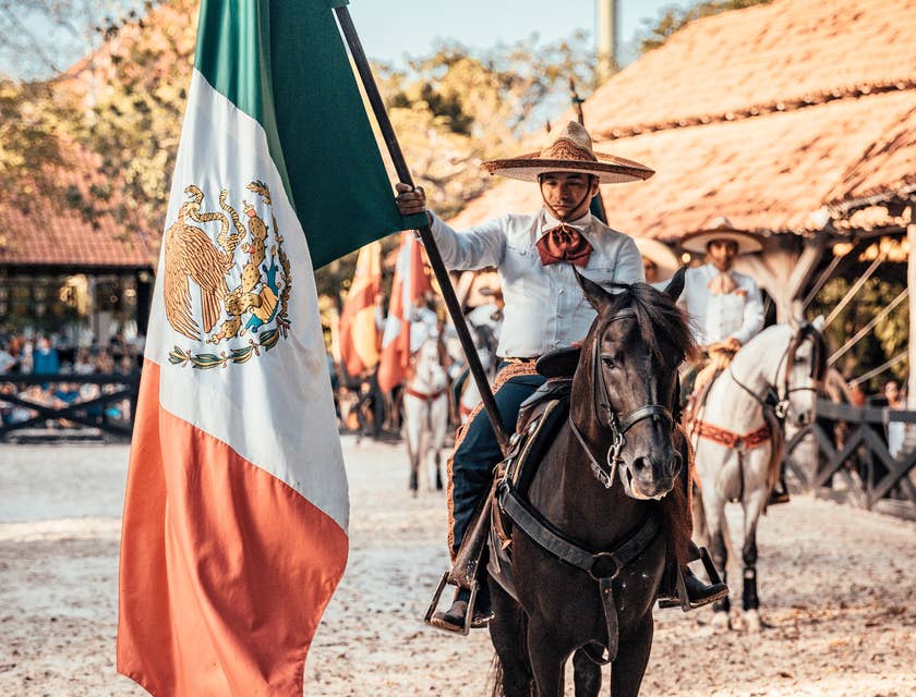 Un charro montando en un caballo con la bandera de México en un negocio de charrería.