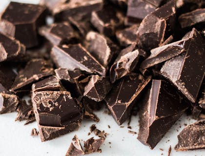 Chocolate en pastillas trozeado sobre una base blanca.